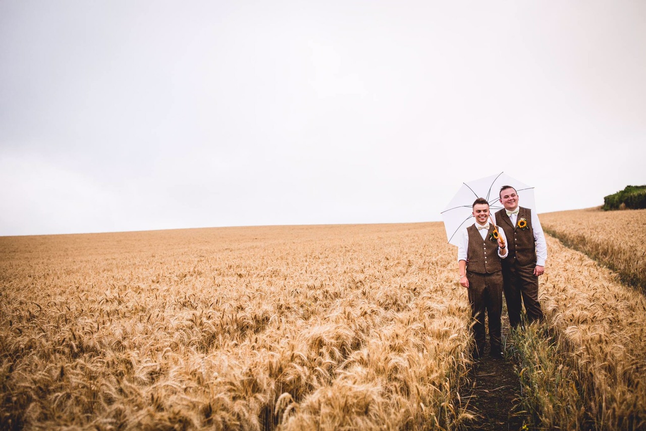 Married male couple in wheatfield in suits